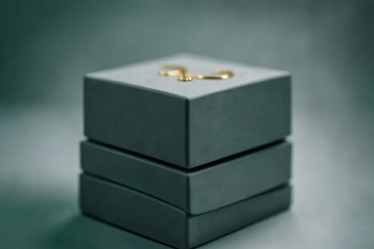Uma composição de blocos cinzas empilhados com um detalhe dourado no topo, representando planejamento e solidez.