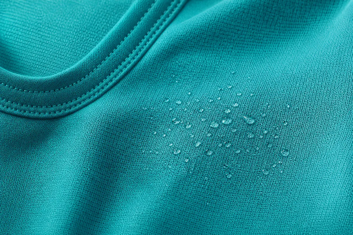 Detalhe de tecido de top fitness com tecnologia de absorção de suor, mostrando a trama.