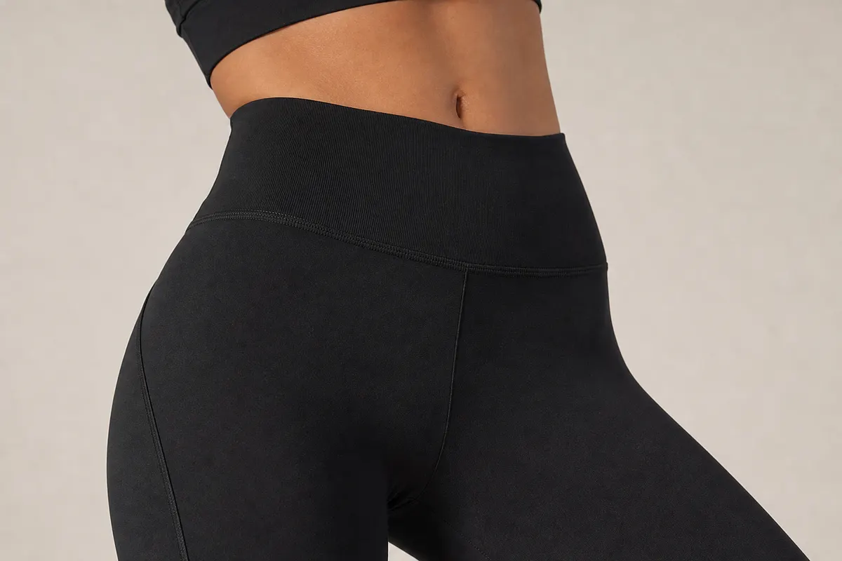 Close-up de uma legging de yoga preta de cintura alta com textura sutil, mostrando a qualidade do tecido.