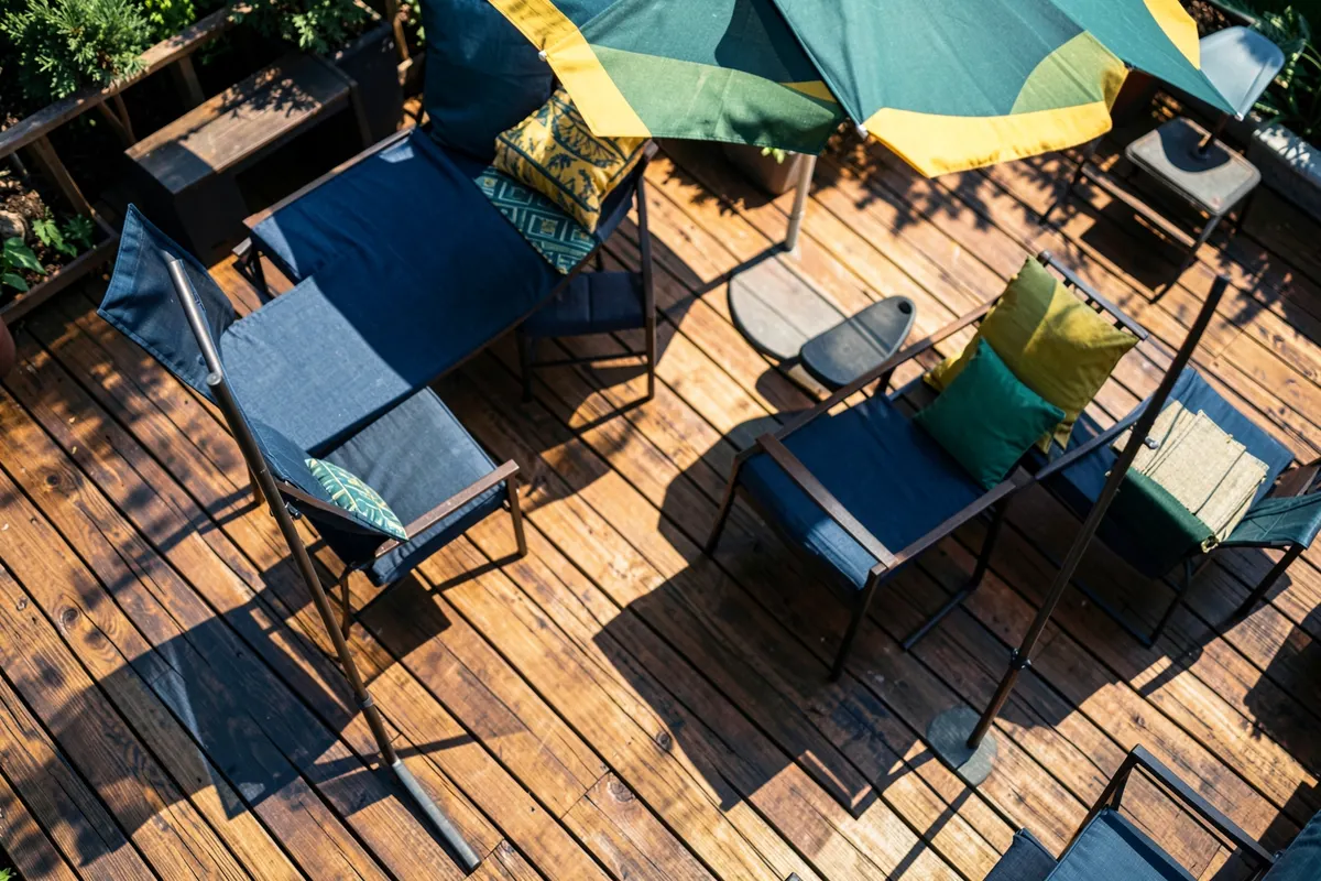 Vista aérea de um deck de madeira com móveis de jardim e guarda-sol