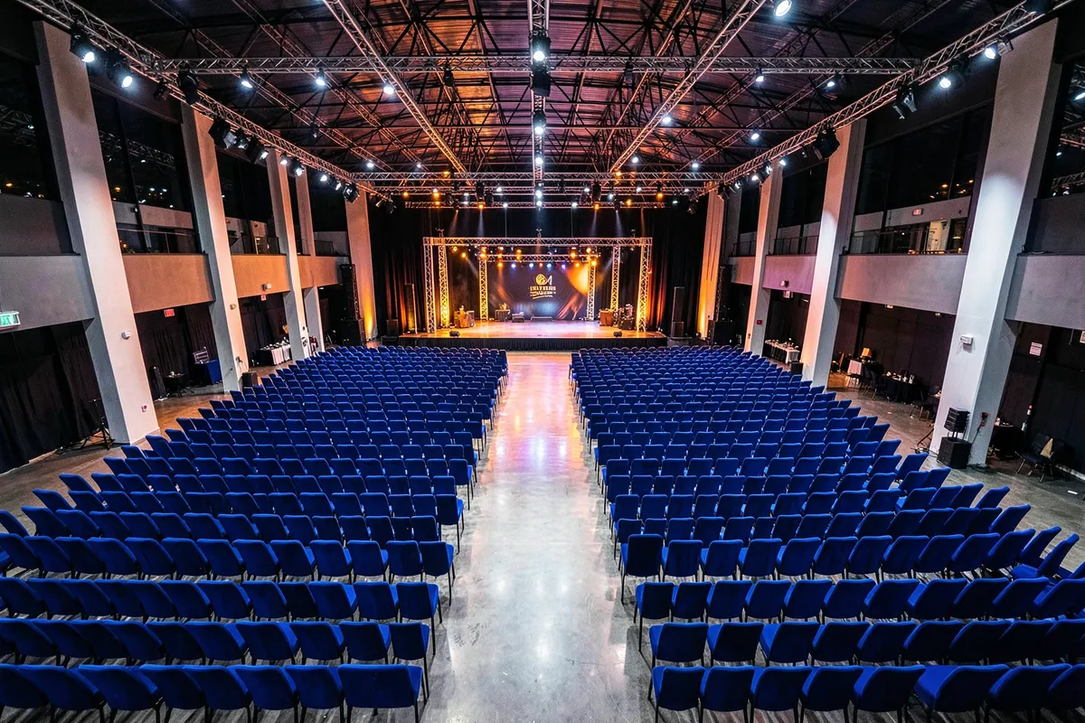 Vista aérea de um salão de eventos amplo e bem iluminado, com cadeiras dispostas em fileiras para uma apresentação ou conferência.