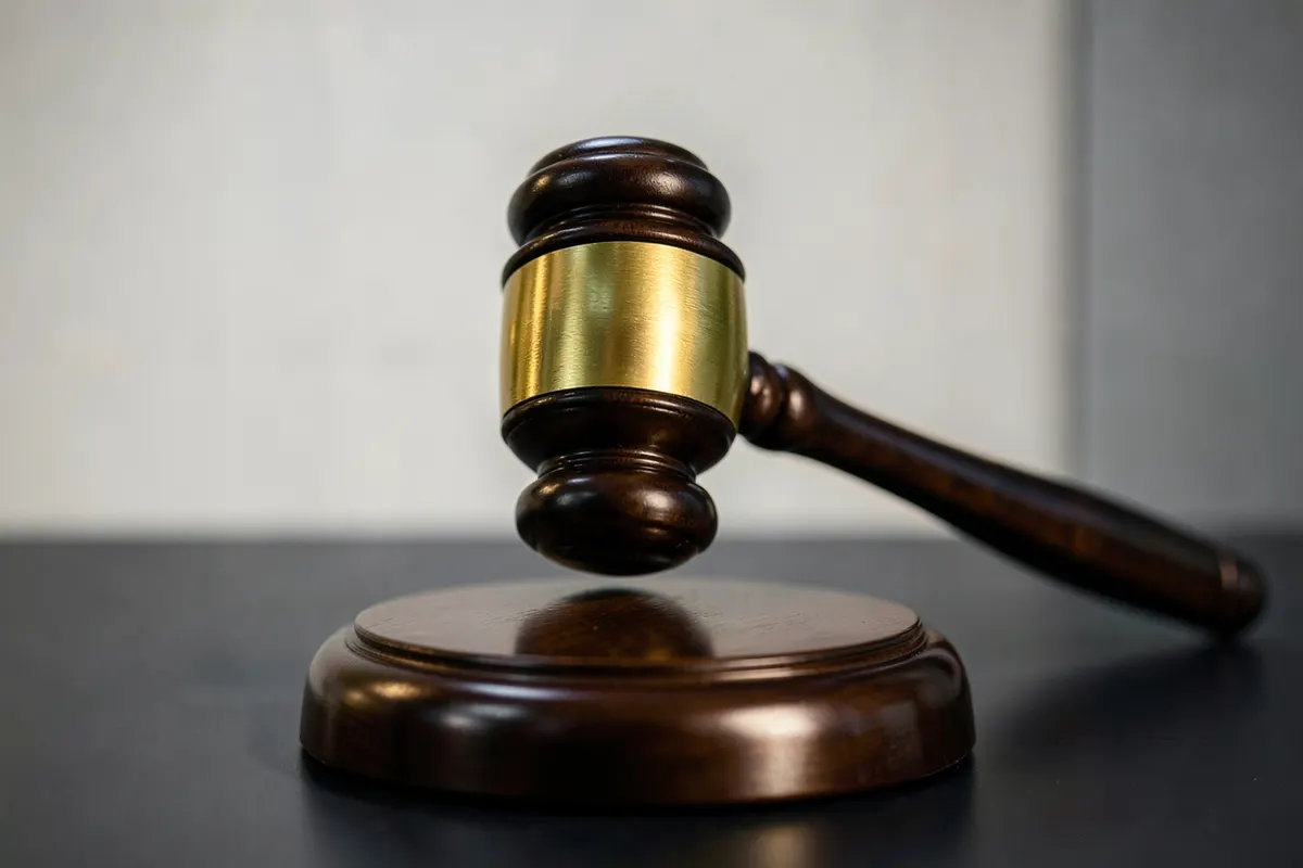 Um martelo de juiz batendo sobre um bloco de madeira, simbolizando justiça e legalidade.