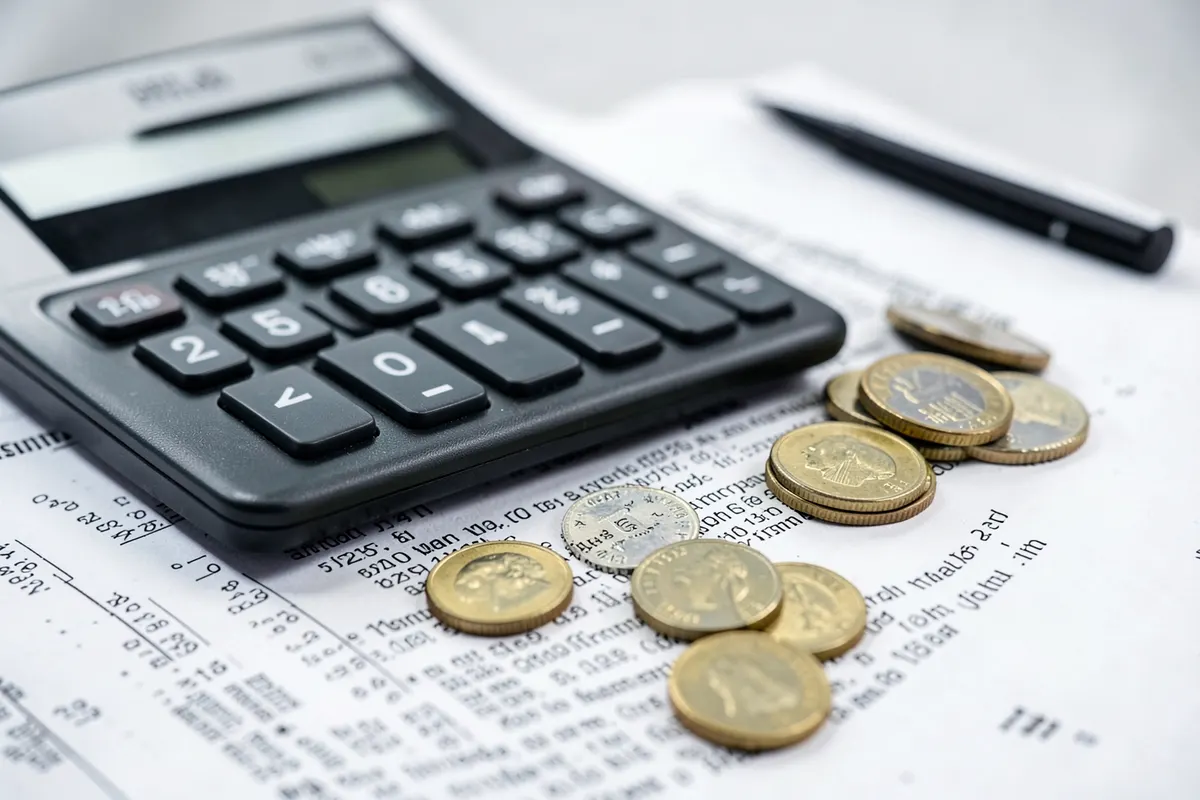Uma calculadora e moedas sobre um documento legal.