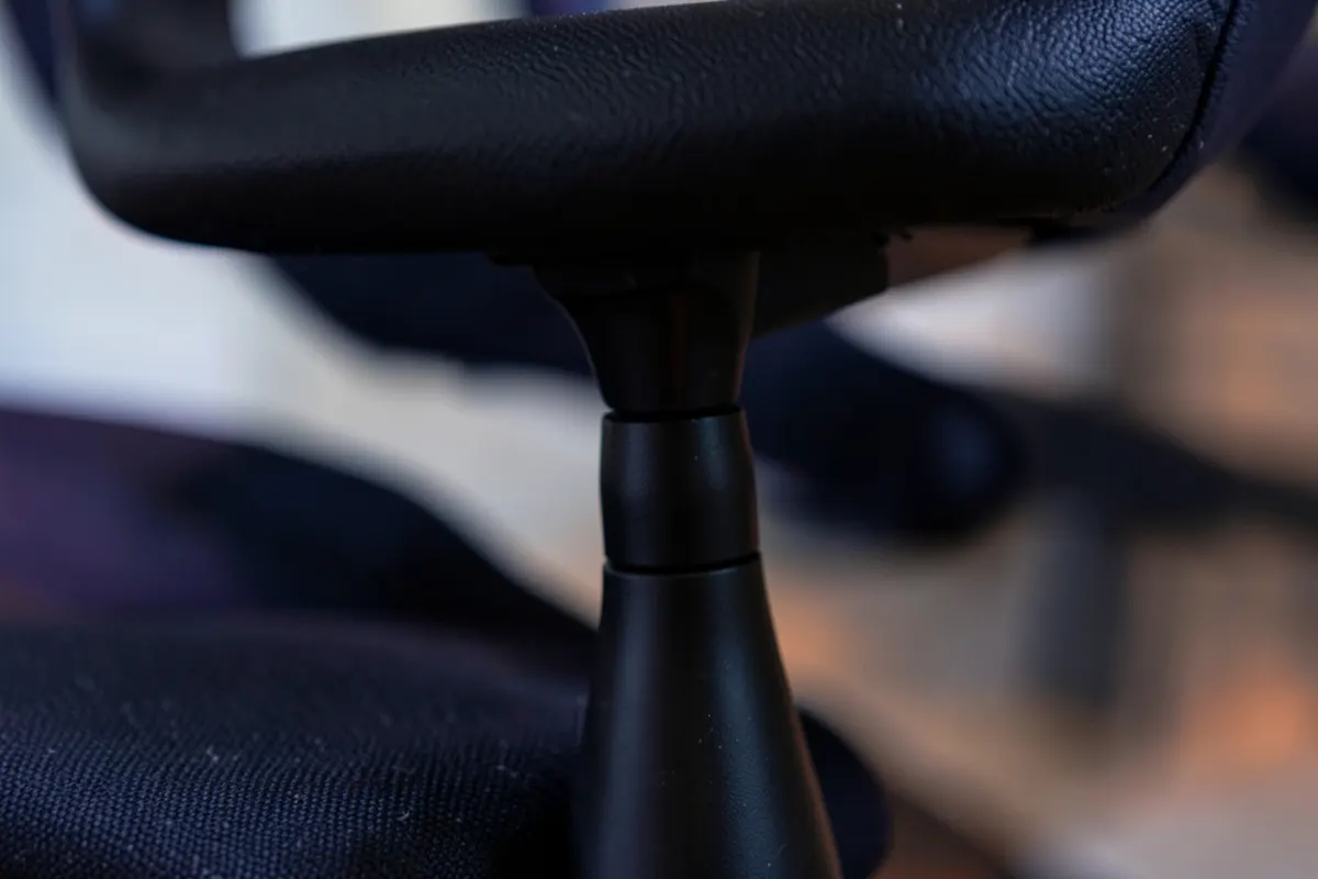 Close-up de uma pessoa ajustando a altura de uma cadeira de escritório ergonômica.