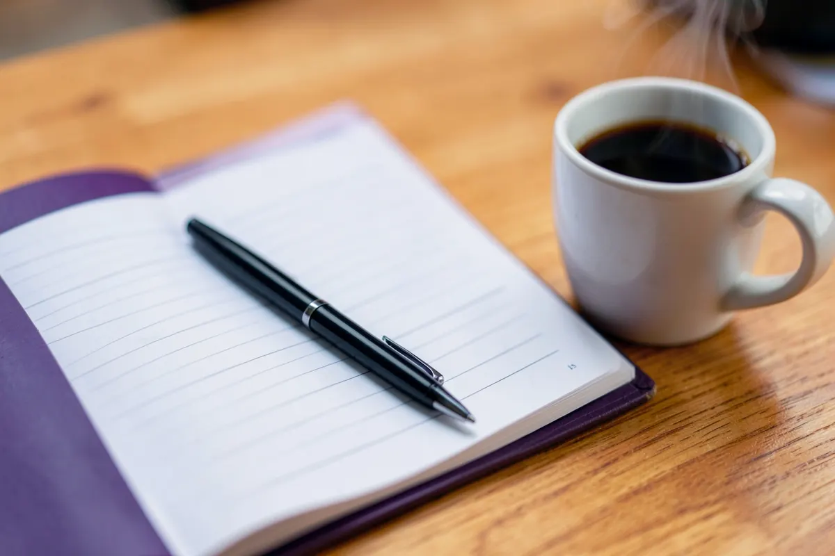 Um plano de negócios aberto em uma mesa com uma caneta e um copo de café.
