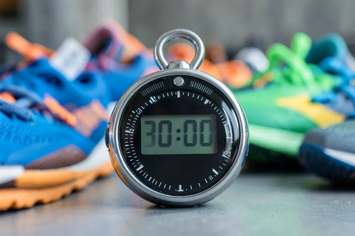 Um cronômetro digital marcando 30 minutos sobre um fundo desfocado de tênis de corrida.