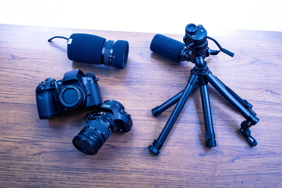 Equipamento de produção de vídeo como câmera, microfone e tripé organizados em uma mesa