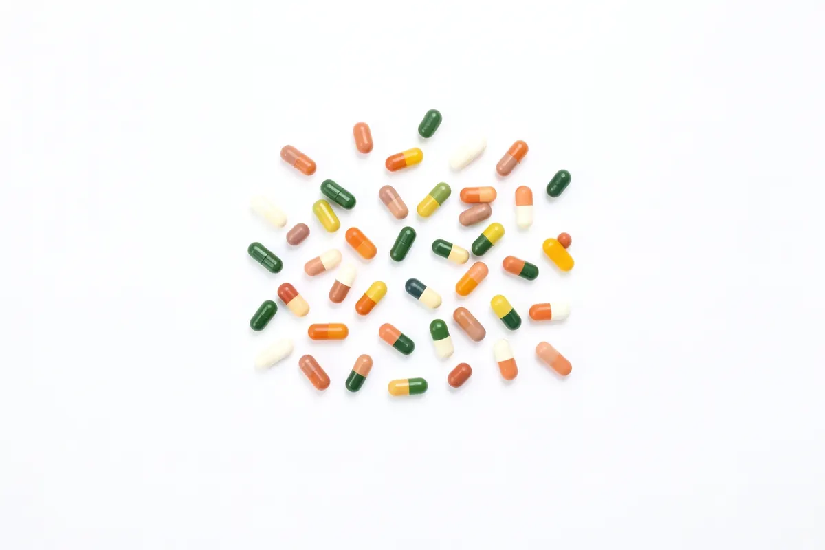 Uma variedade de pílulas e cápsulas coloridas dispostas em um fundo branco.