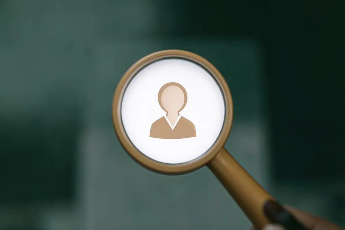 Uma lupa examinando um ícone de perfil de médico em uma tela de computador.