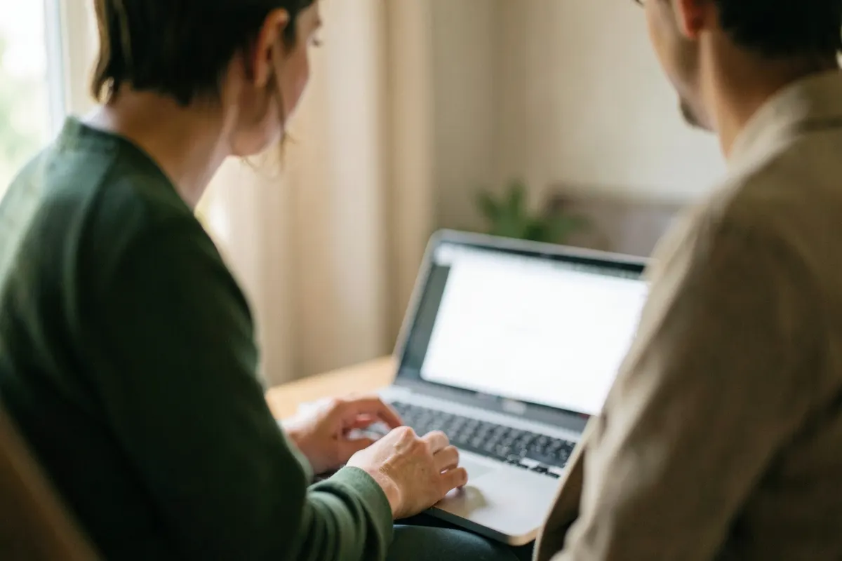 Uma pessoa sentada em frente a um laptop com um sorriso, em uma consulta online.