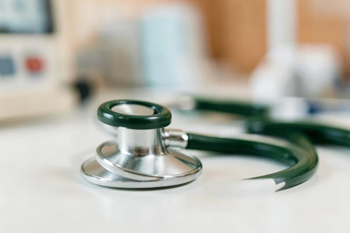Um close-up de um estetoscópio sobre um fundo desfocado de um consultório médico.