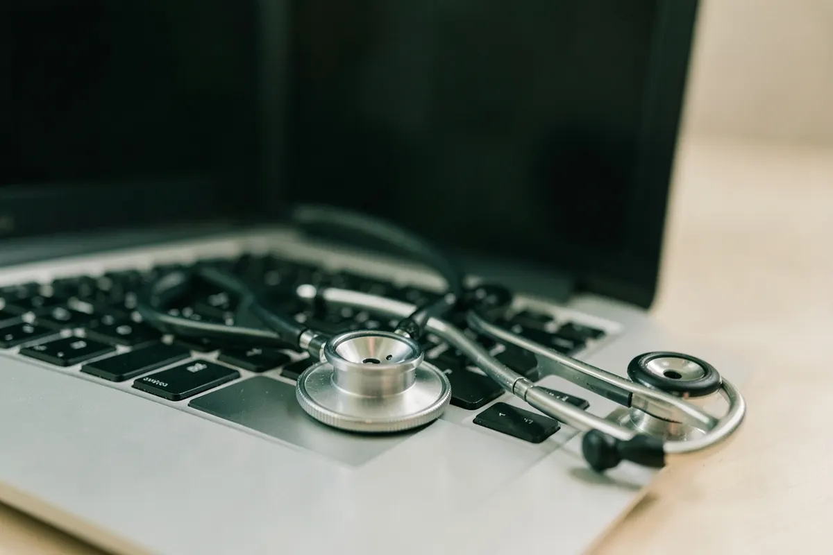 Um estetoscópio sobre um teclado de laptop, simbolizando a conexão entre tecnologia e saúde.