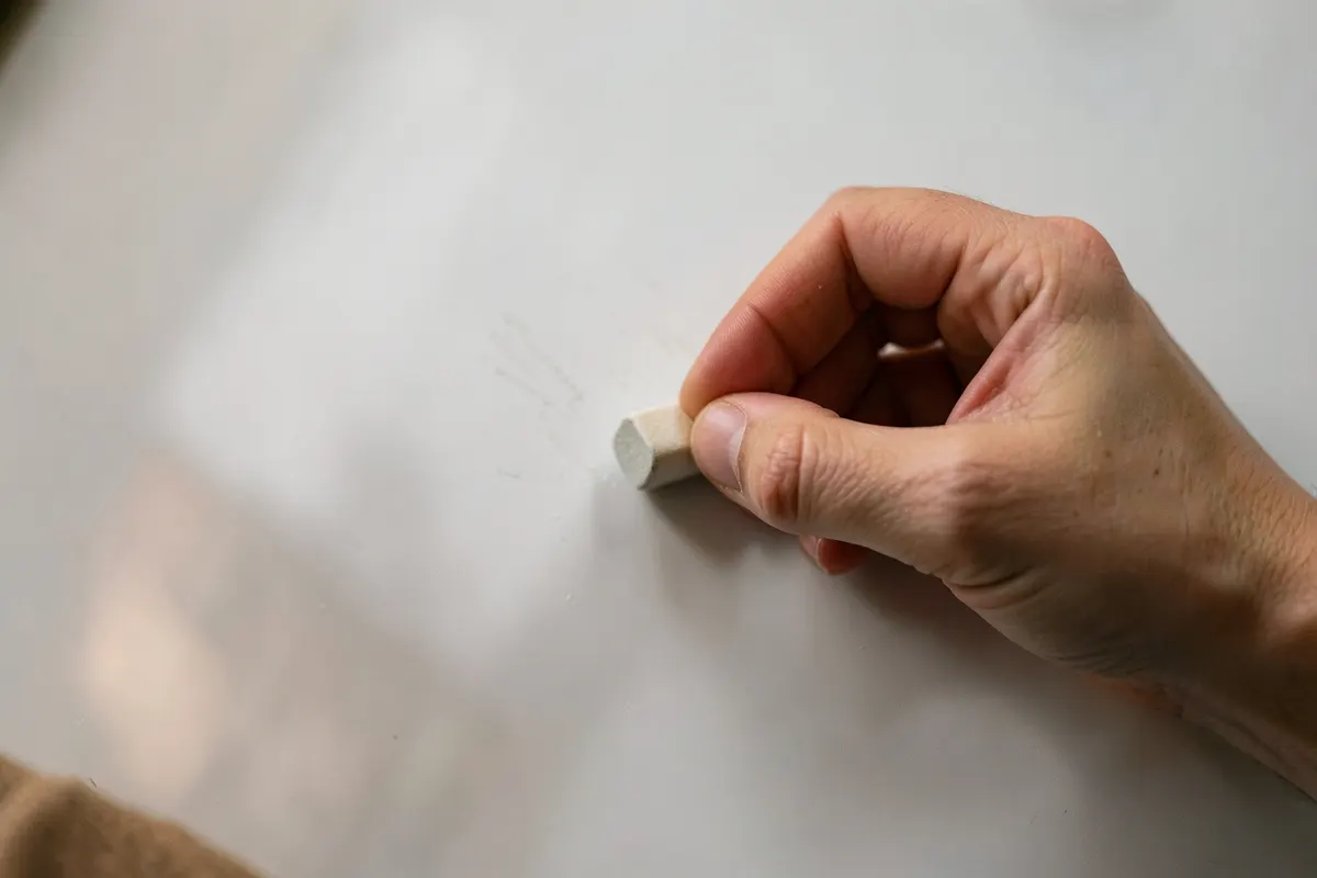 Pessoa apagando um quadro branco com uma borracha, deixando-o limpo.