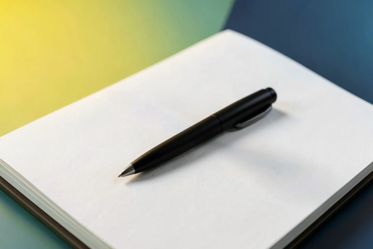 Uma caneta preta sobre um caderno aberto com páginas brancas, em close-up, com luz suave vinda da esquerda, em um momento de escrita.