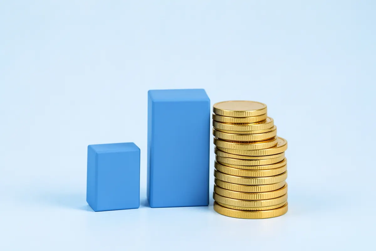 Um gráfico de barras ascendente com moedas de ouro empilhadas ao lado, em um fundo azul claro.