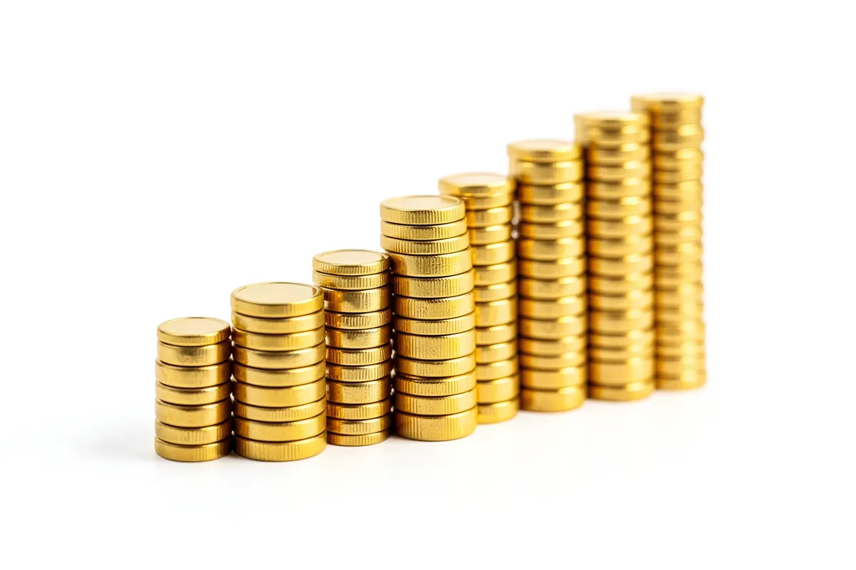 Um gráfico de barras ascendente feito de moedas de ouro empilhadas, em um fundo branco limpo.