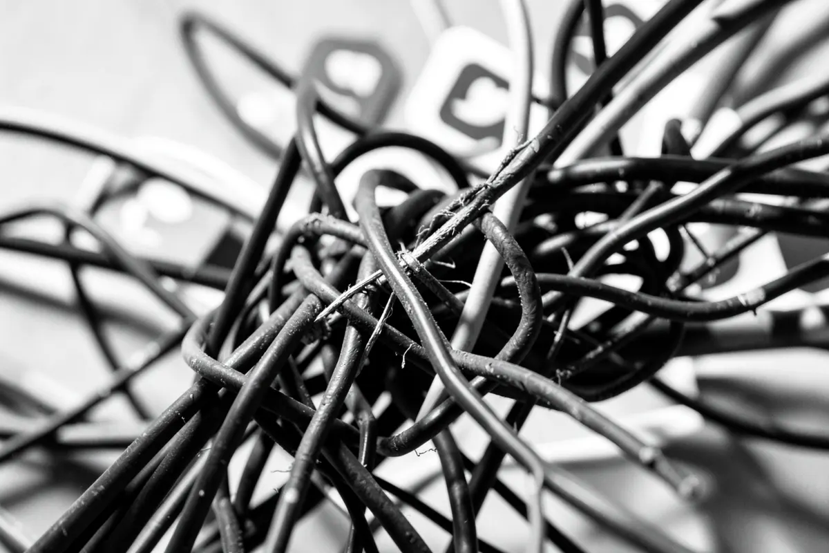 Um emaranhado de fios e cabos conectados a vários ícones de redes sociais desfocados
