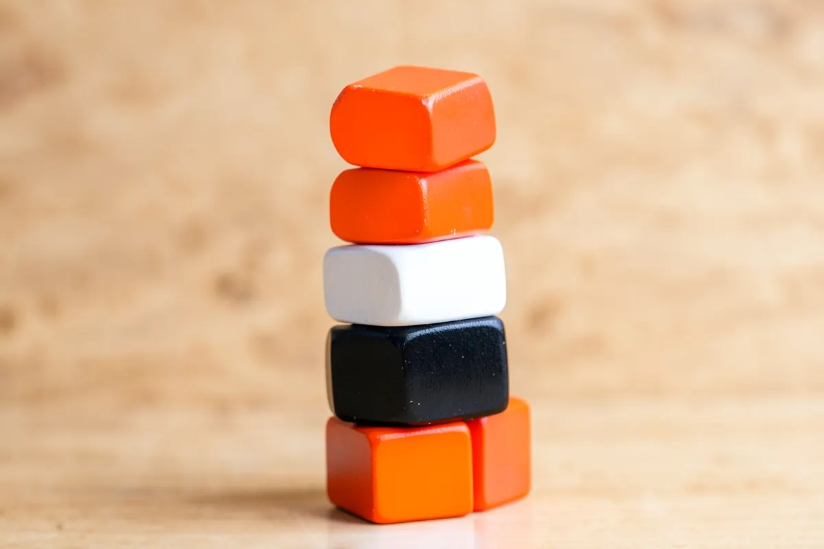 Um conjunto de blocos de madeira coloridos empilhados formando uma torre instável, com um fundo de textura de madeira.