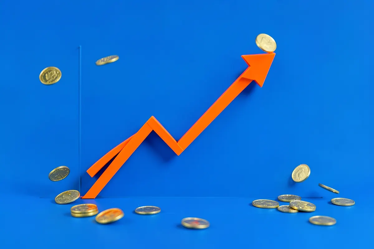 Um gráfico de linha ascendente com moedas de ouro caindo ao redor, sobre um fundo azul.